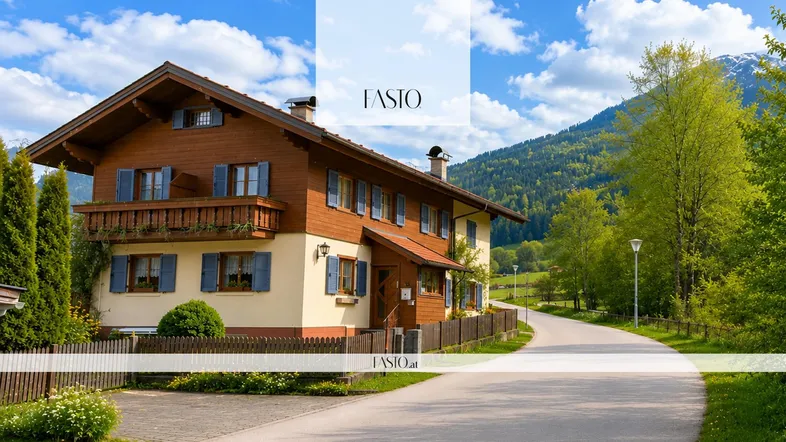 Traditionelles Alpenhaus mit Holzfassade, blauen Fensterläden und Balkon in grüner Umgebung.