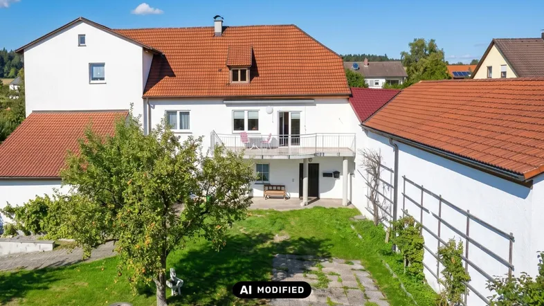 Weißes Wohnhaus mit rotem Ziegeldach, Balkon und großem Gartenbereich.