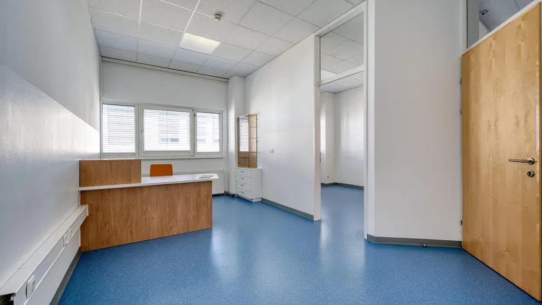 Heller Büroraum mit Empfangstheke, blauer Boden und abgehängter Decke, ideal für gewerbliche Nutzung.
