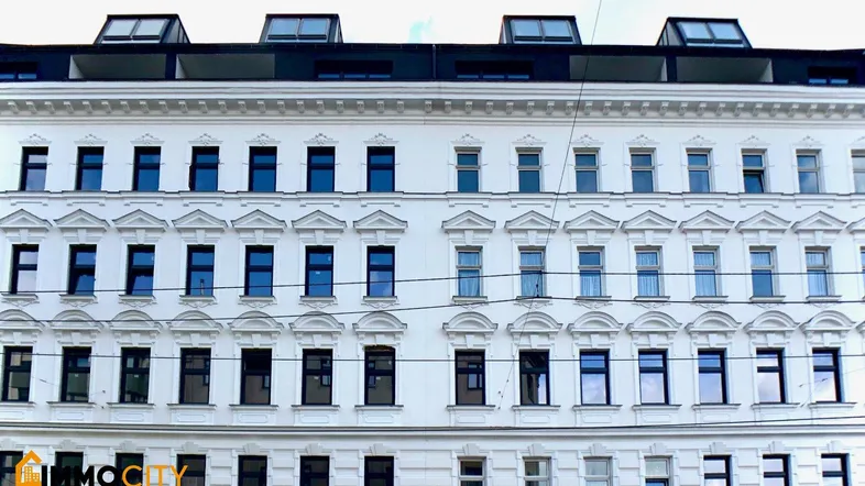 Fassade eines Altbaus mit vielen Fenstern und modernen Dachgauben.