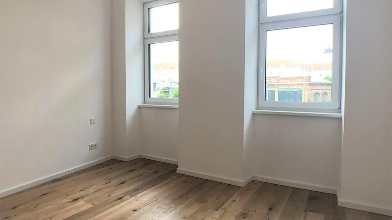Helles Zimmer mit neuem Holzboden und zwei Fenstern, bereit für die individuelle Gestaltung.