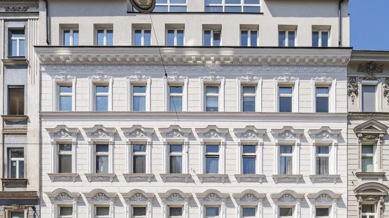 Klassische Fassade eines Altbaus mit modernen Dachgeschossfenstern und Verzierungen.
