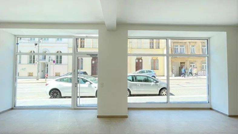 Heller, leerer Raum mit großen Fenstern und Blick auf die Straße, ideal für verschiedene Nutzungen.