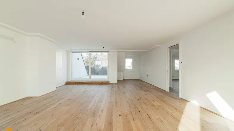 Geräumiges, helles Zimmer mit Holzboden und großer Schiebetür, die Zugang zum Außenbereich bietet.