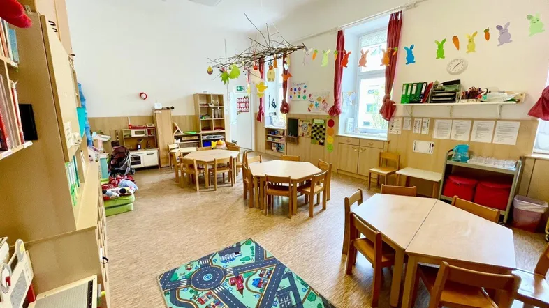 Geräumiger Spielraum mit Kindermöbeln, Regalen und bunten Dekorationen, ideal für eine Kindergruppe.