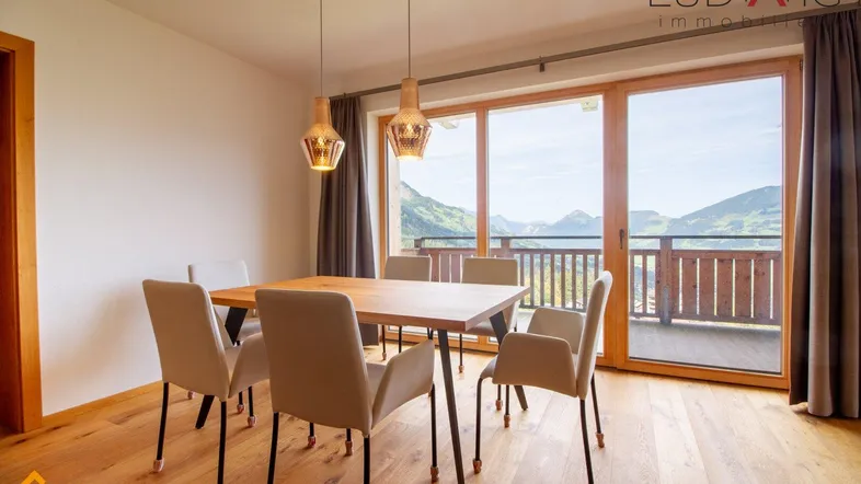 Heller Essbereich mit Holzboden und großen Fenstern, die einen weiten Bergblick bieten.