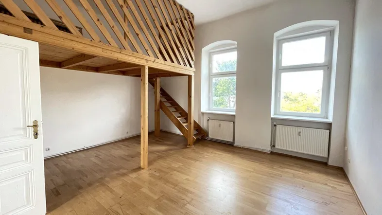 Heller Raum mit Holzboden und einer charmanten Holzgalerie, ideal für flexibles Wohnen.