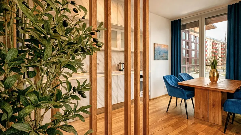 Moderne offene Küche mit Essbereich, Holzboden und dekorativem Raumteiler.