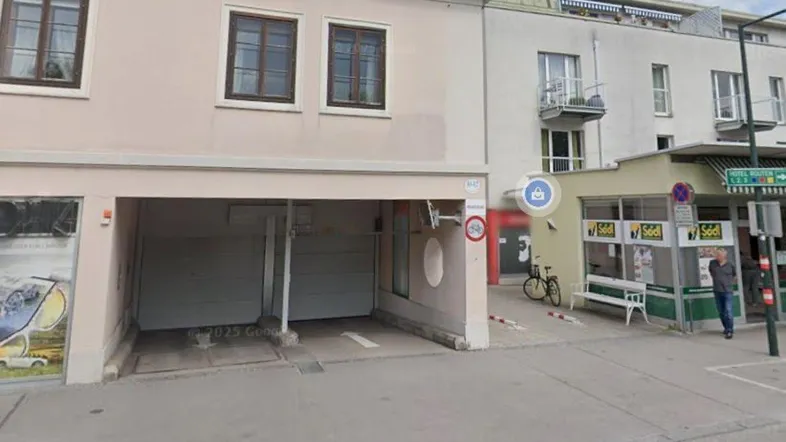 Eingang zur Tiefgarage in einem Gebäude mit Geschäften an der Straße.