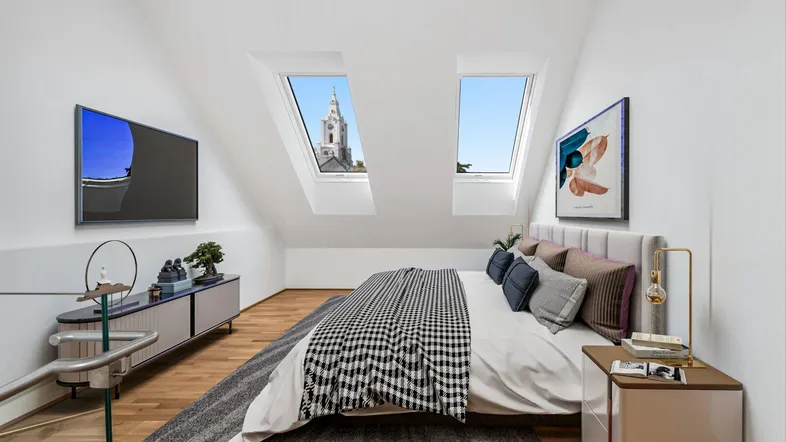 Helles Schlafzimmer im Dachgeschoss mit Holzboden, Dachfenstern und Blick auf einen Kirchturm.