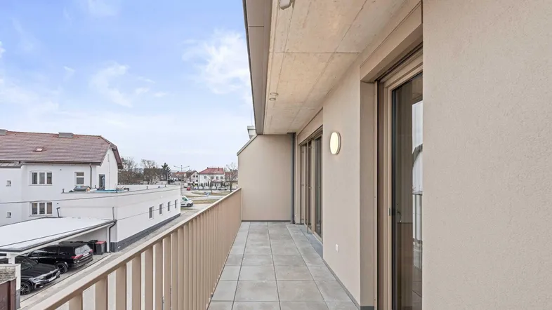 Geräumiger Balkon mit Fliesenboden und Blick auf die Umgebung, ideal für entspannte Stunden im Freien.