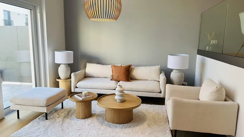 Helles Wohnzimmer mit bequemen Möbeln, Holzboden und Zugang zu einem Außenbereich.