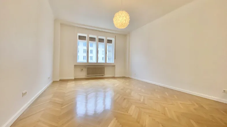 Heller, leerer Raum mit elegantem Fischgrätparkettboden und großen Fenstern, bereit zur individuellen Gestaltung.