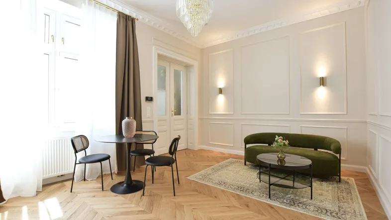 Helles Wohnzimmer mit Fischgrätparkett, Stuckelementen und moderner Einrichtung.