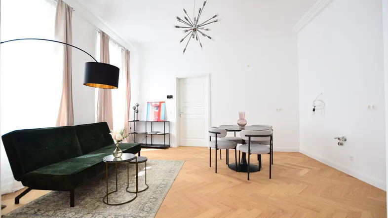 Helles Wohn- und Esszimmer mit Fischgrätparkett, moderner Einrichtung und hohen Decken.