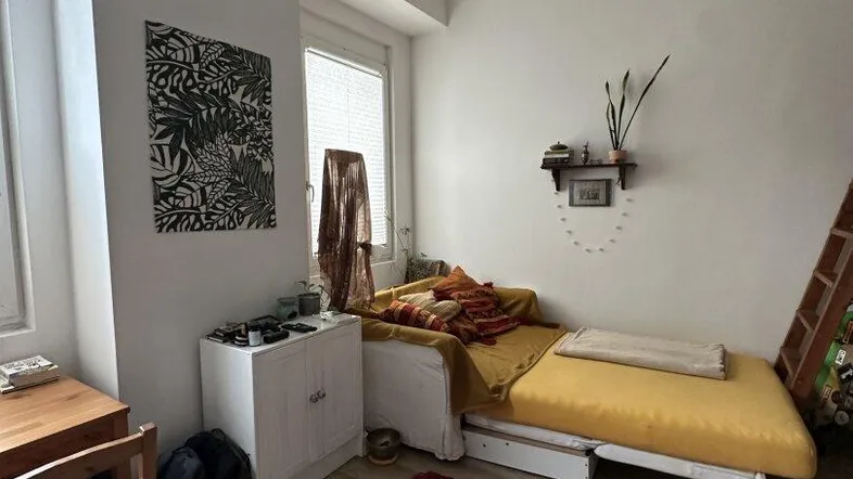 Helles Schlafzimmer mit Einzelbett, Schreibtisch und Fenster, ausgestattet mit Laminatboden.