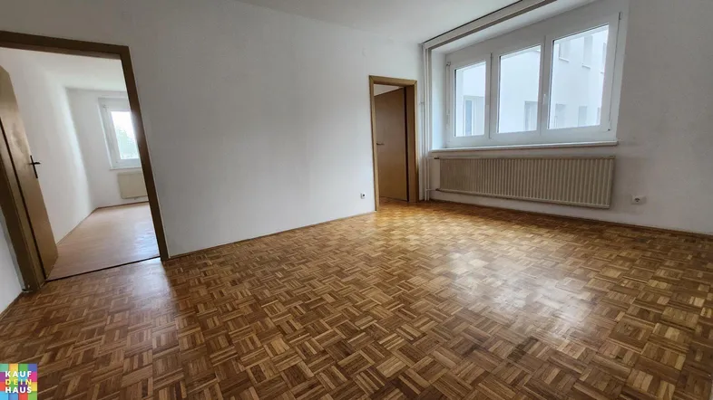 Helles Zimmer mit Parkettboden und weißen Wänden, bereit zur individuellen Gestaltung.
