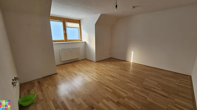 Helles Zimmer mit Parkettboden, Dachschräge und Fenster, ideal als Schlaf- oder Wohnbereich.