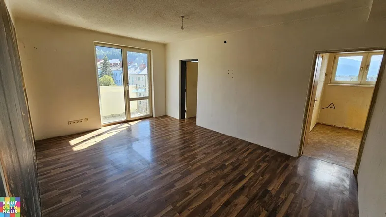 Helles Zimmer mit Laminatboden und Zugang zu einem Balkon, ideal als Wohn- oder Schlafbereich.