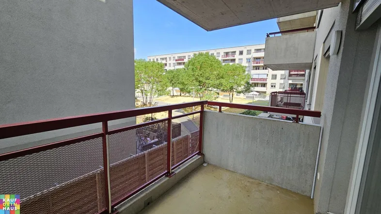 Balkon mit Blick auf den begrünten Innenhof und umliegende Gebäude.