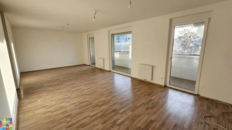 Helles Wohnzimmer mit Holzboden und Zugang zu einem Balkon, ideal für individuelle Gestaltung.