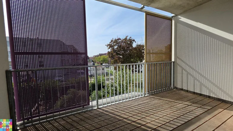 Geräumiger Balkon mit Holzboden und perforierten Sichtschutzwänden, bietet einen Blick ins Grüne.