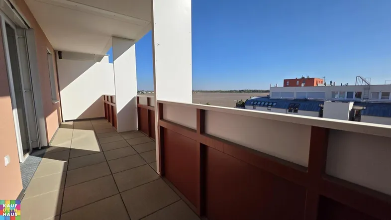 Heller Balkon mit Fliesenboden und weitem Blick auf die Umgebung unter blauem Himmel.