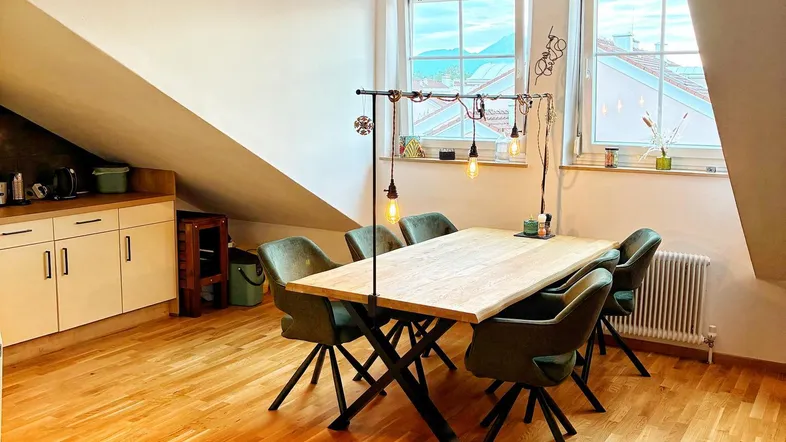 Heller Essbereich mit Holztisch, modernen Stühlen und Dachschrägenfenstern mit Ausblick ins Grüne.
