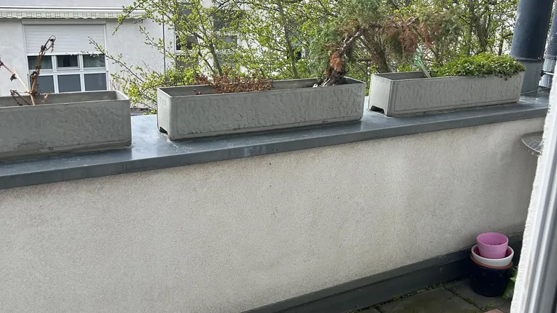 Schmaler Balkon mit Pflanzkübeln und Blick auf die umliegenden Gebäude.