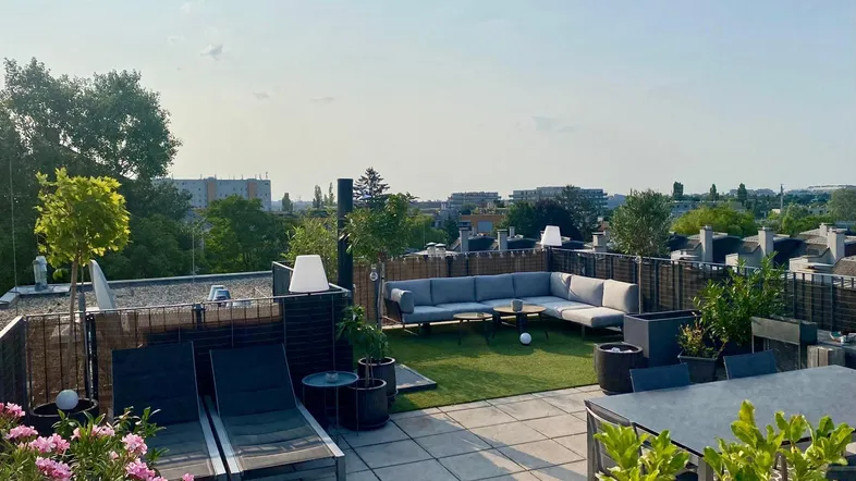 Geräumige Dachterrasse mit Lounge-Bereich, Sonnenliegen und Blick über die Stadt.