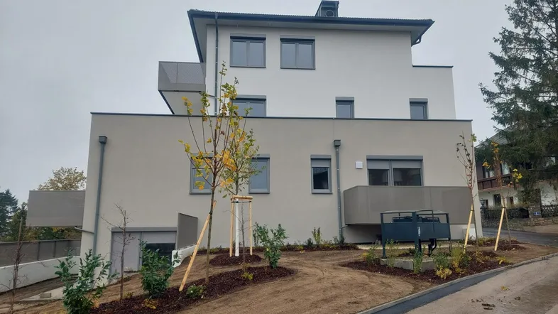 Modernes Mehrfamilienhaus mit mehreren Etagen, Balkonen und neu angelegten Außenbereichen.