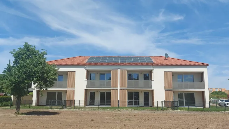 Modernes Mehrfamilienhaus mit Balkonen, Photovoltaikanlage auf dem Dach und neu angelegtem Grundstück.