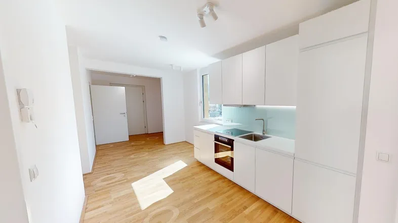 Moderne, helle Küche mit weißen Schränken, Holzboden und offener Gestaltung zum Wohnbereich.