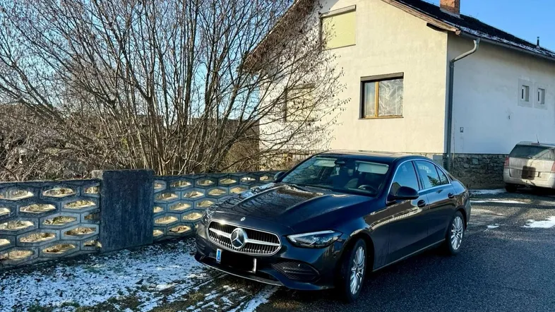 Einfamilienhaus an einer ruhigen Straße mit einem geparkten Auto im Vordergrund.