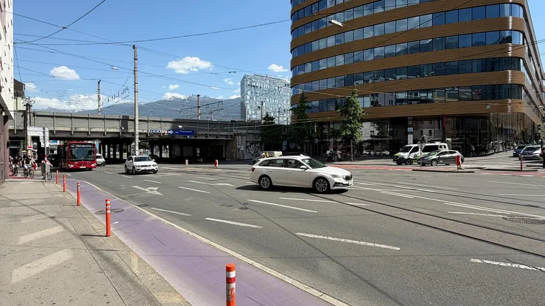Moderne Architektur und städtische Umgebung mit Straßenverkehr und Bergen im Hintergrund.