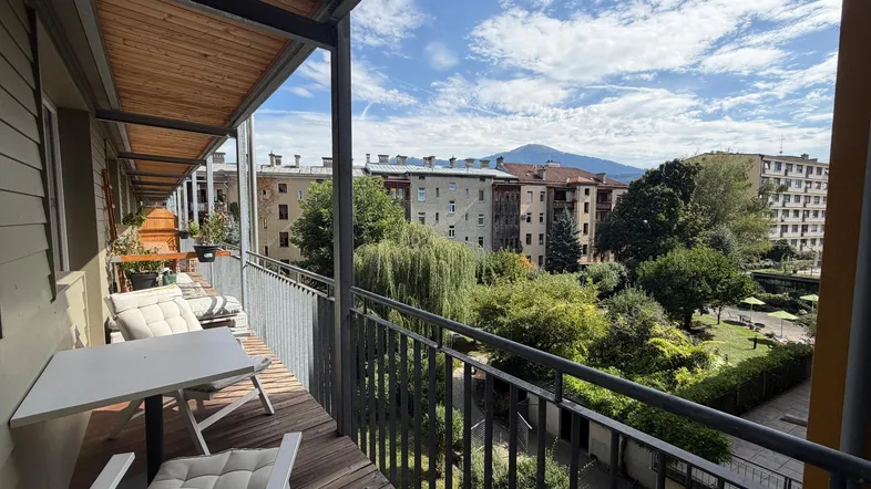Geräumiger Balkon mit Holzboden, Sitzgelegenheiten und weitem Blick auf die Berge und die Umgebung.