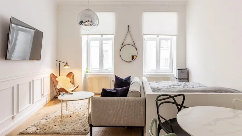 Helles Wohnzimmer mit Parkettboden, weißer Wandverkleidung und einem gemütlichen Sofa.