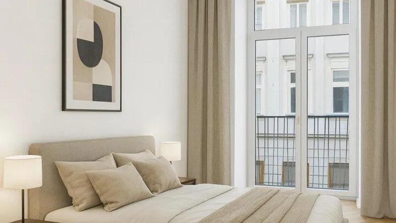 Helles Schlafzimmer mit modernem Bett, Nachttischen und Zugang zu einem französischen Balkon.