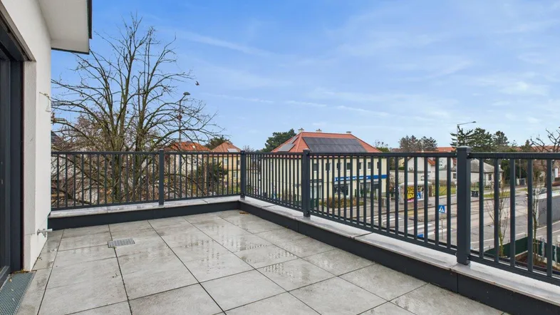 Geräumige Terrasse mit Fliesenboden und Blick auf die Umgebung, ideal für Entspannung im Freien.
