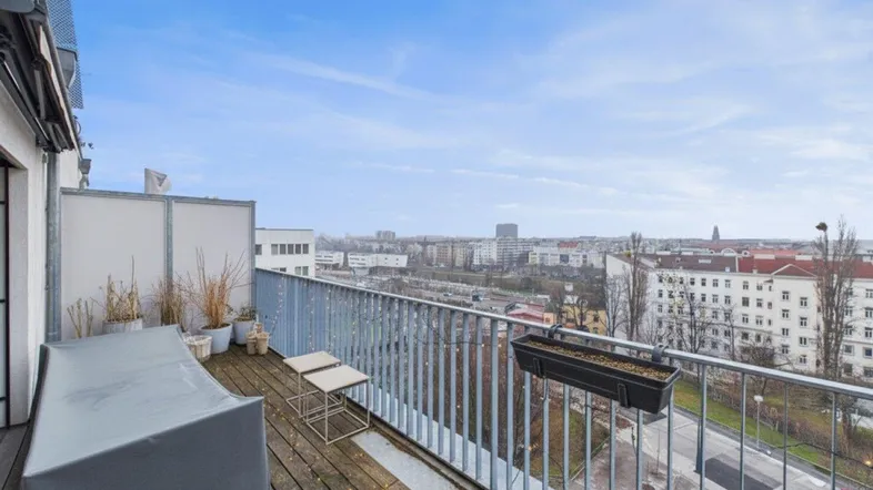 Geräumiger Balkon mit Holzboden und weitem Blick über die Stadtlandschaft.