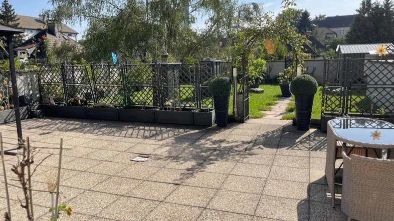 Geräumige gepflasterte Terrasse mit Gartenmöbeln und Blick auf den grünen Gartenbereich.