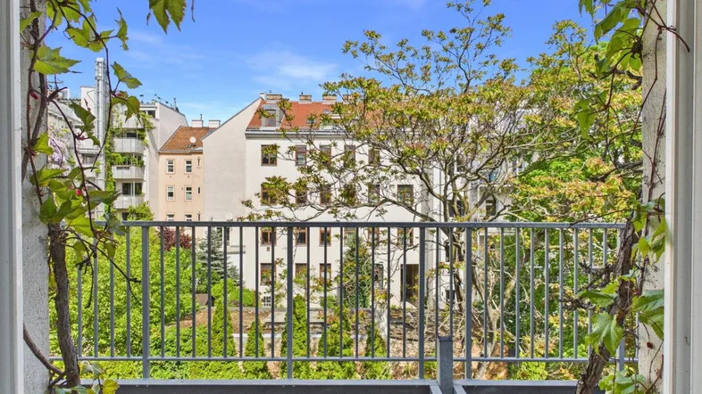 Blick vom Balkon auf die umliegenden Gebäude und viel Grün in der Stadt.