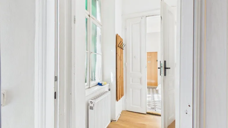 Heller Flur mit Holzfußboden, großem Fenster und Zugang zu weiteren Räumen.