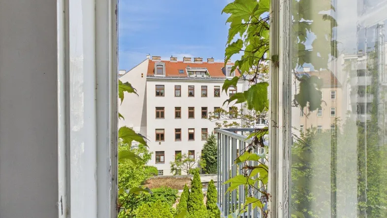 Blick aus dem Fenster auf die umliegenden Gebäude und viel Grün in der Stadt.