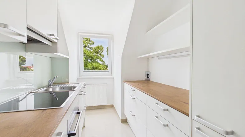 Moderne Küche mit weißen Schränken, Holz-Arbeitsplatten und einem Fenster mit Blick ins Grüne.