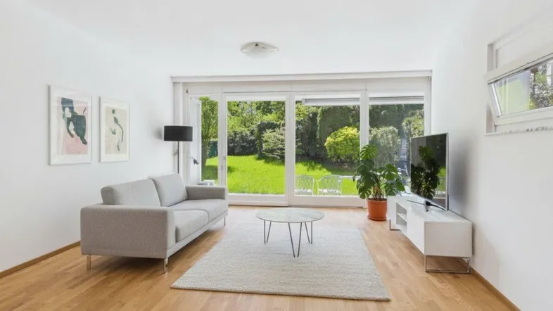 Helles Wohnzimmer mit Holzboden, moderner Einrichtung und direktem Zugang zum grünen Garten.