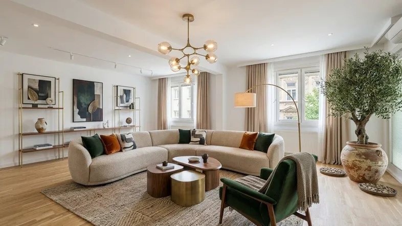 Helles, modern eingerichtetes Wohnzimmer mit beigem Sofa, grünem Sessel und Holzboden.