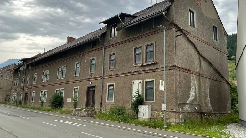 Ansicht der langen Fassade eines Mehrfamilienhauses mit mehreren Fenstern und einem Satteldach.