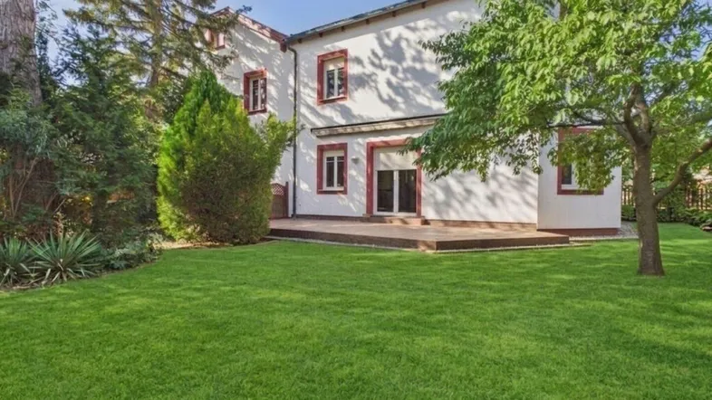 Gepflegter Gartenbereich mit großer Rasenfläche und Zugang zur Terrasse des Hauses.