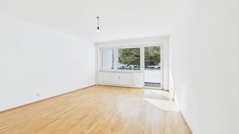 Helles, leeres Zimmer mit Parkettboden und Zugang zu einem Balkon, bereit zur individuellen Gestaltung.